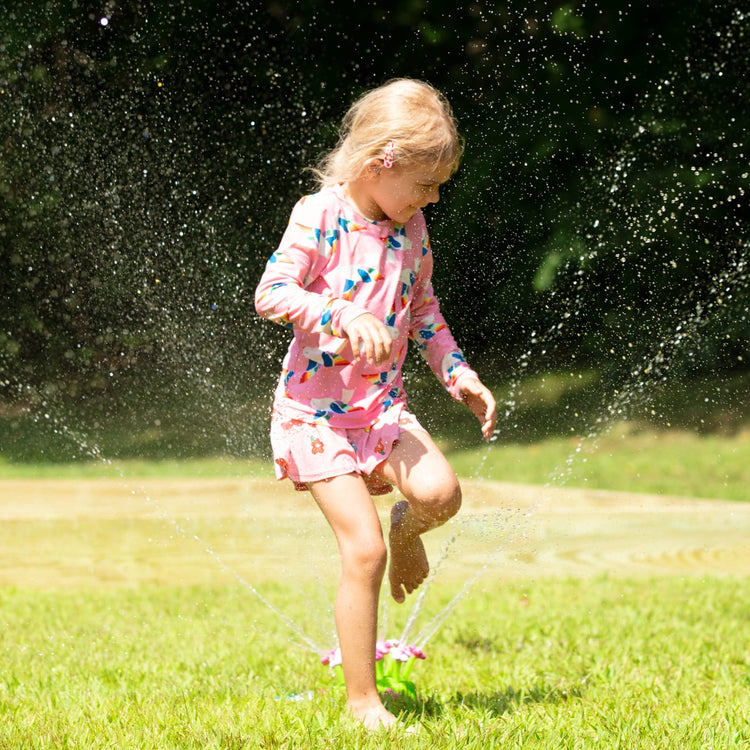 A kid playing with the Melissa & Doug Sunny Patch Pretty Petals Flower Sprinkler Toy With Hose Attachment