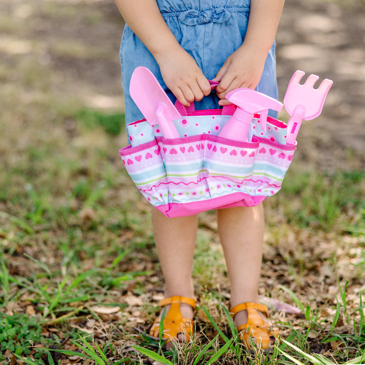 A kid playing with the Melissa & Doug Sunny Patch Pretty Petals Gardening Tote Set With Tools