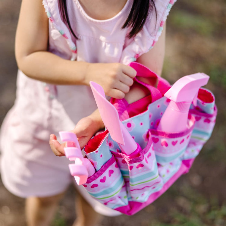 A kid playing with the Melissa & Doug Sunny Patch Pretty Petals Gardening Tote Set With Tools