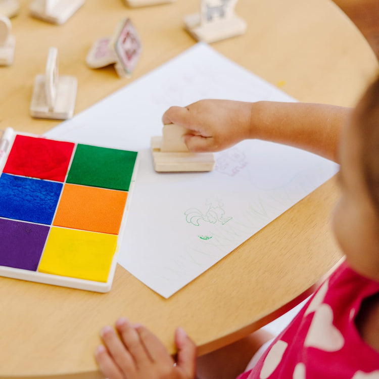 A kid playing with the Melissa & Doug Rainbow Stamp Pad - 6 Washable Inks