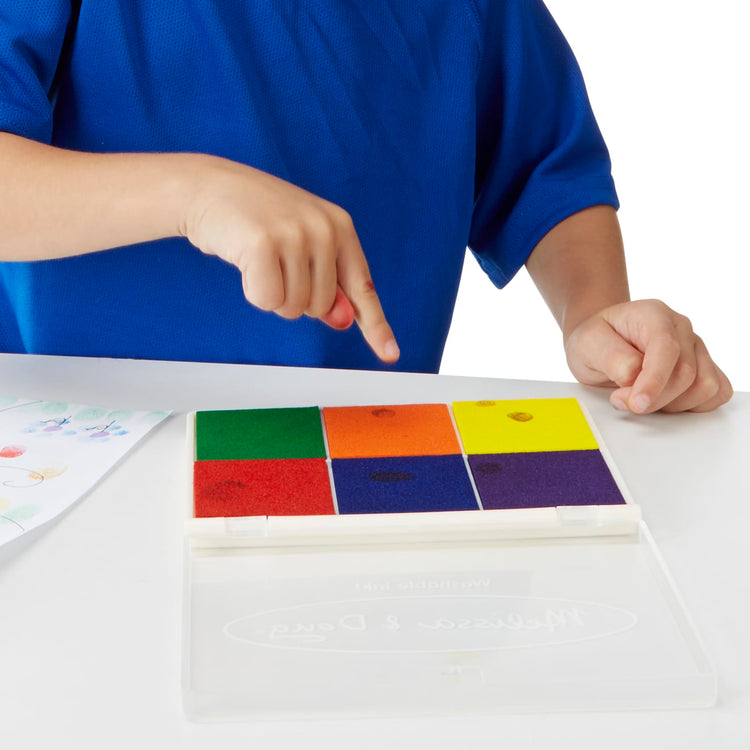 A child on white background with the Melissa & Doug Rainbow Stamp Pad - 6 Washable Inks