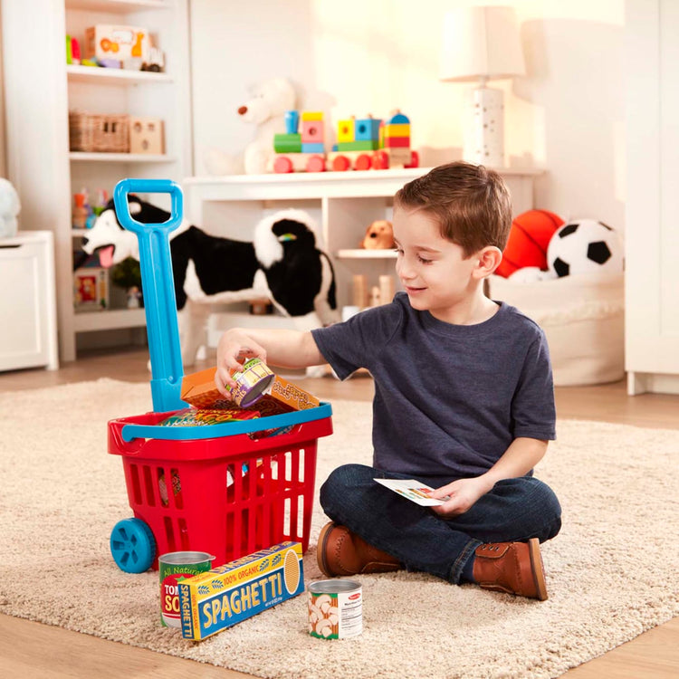 A kid playing with the Melissa & Doug Fill and Roll Grocery Basket Play Set With Play Food Boxes and Cans (11 pcs)