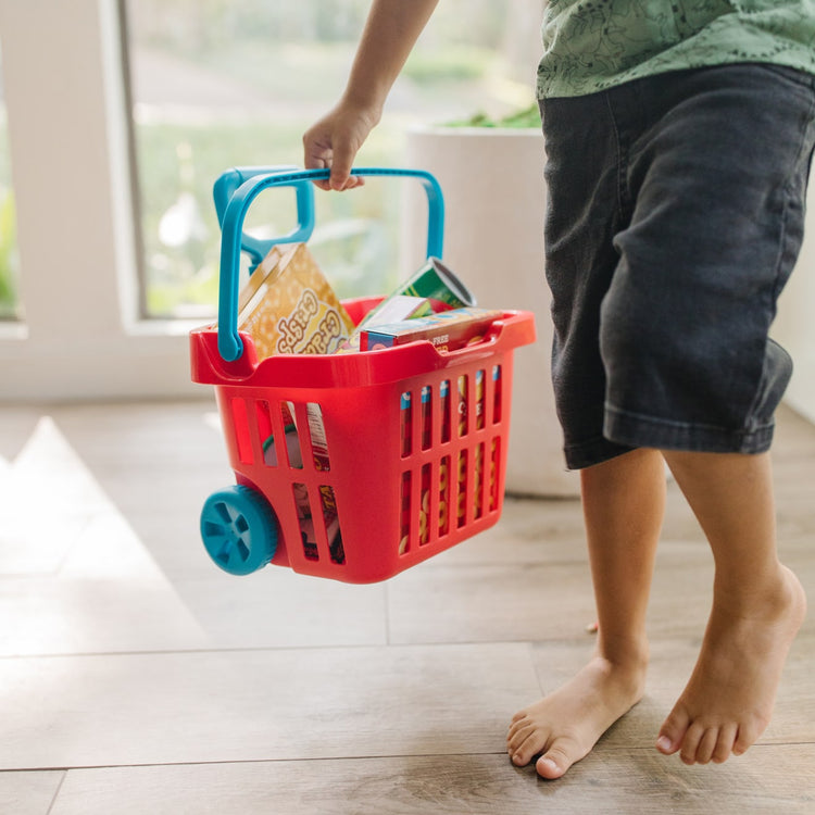 A kid playing with the Melissa & Doug Fill and Roll Grocery Basket Play Set With Play Food Boxes and Cans (11 pcs)