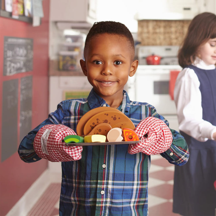 A kid playing with the Melissa & Doug Rotisserie and Grill Wooden Barbecue Play Food Set (24 pcs)