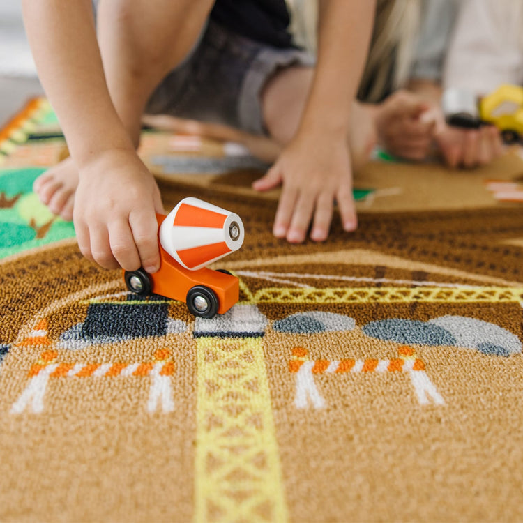 A kid playing with the Melissa & Doug Round the Construction Zone Work Site Rug With 3 Wooden Trucks (39 x 36 inches)