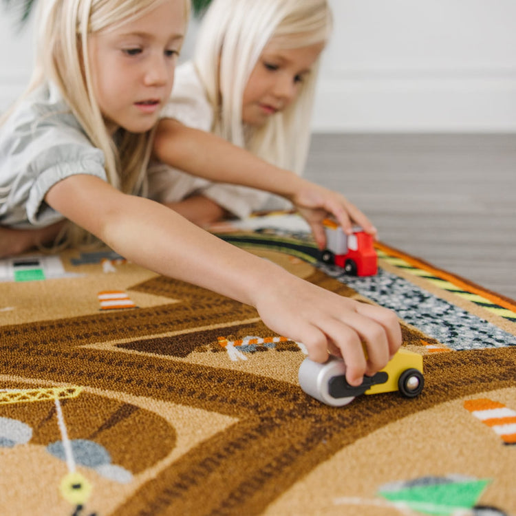 A kid playing with the Melissa & Doug Round the Construction Zone Work Site Rug With 3 Wooden Trucks (39 x 36 inches)