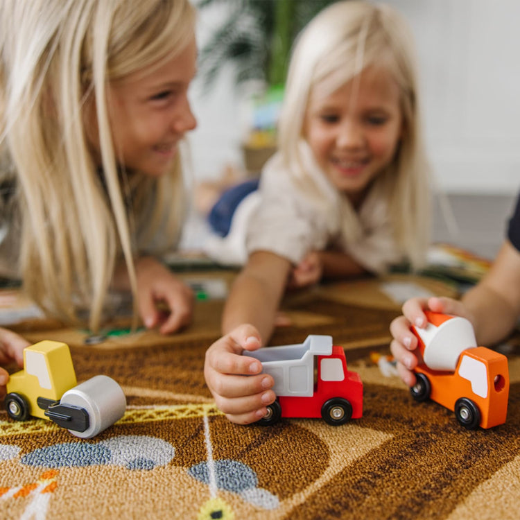 A kid playing with the Melissa & Doug Round the Construction Zone Work Site Rug With 3 Wooden Trucks (39 x 36 inches)