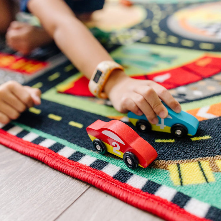 A kid playing with the Melissa & Doug Round the Speedway Race Track Rug With 4 Race Cars (39 x 36 inches)