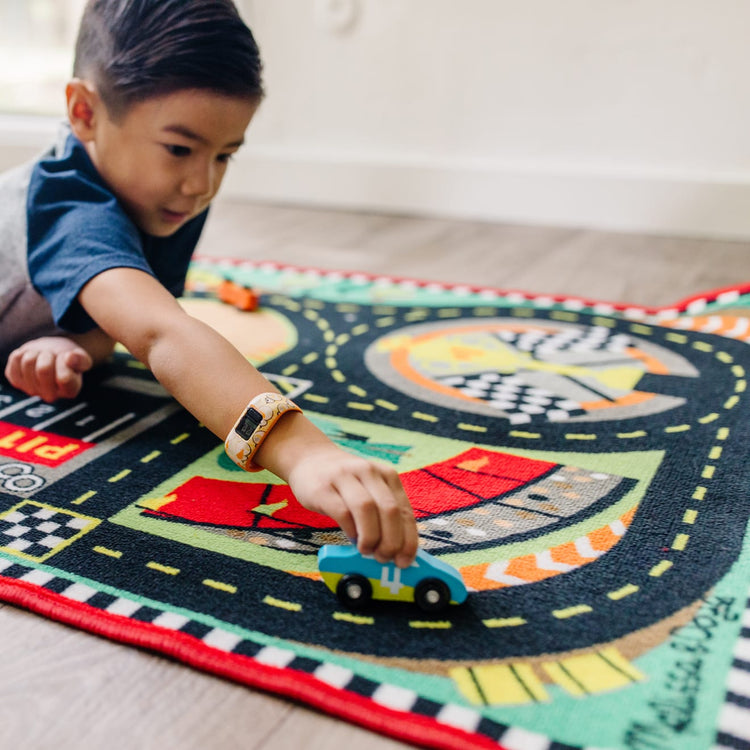 A kid playing with the Melissa & Doug Round the Speedway Race Track Rug With 4 Race Cars (39 x 36 inches)