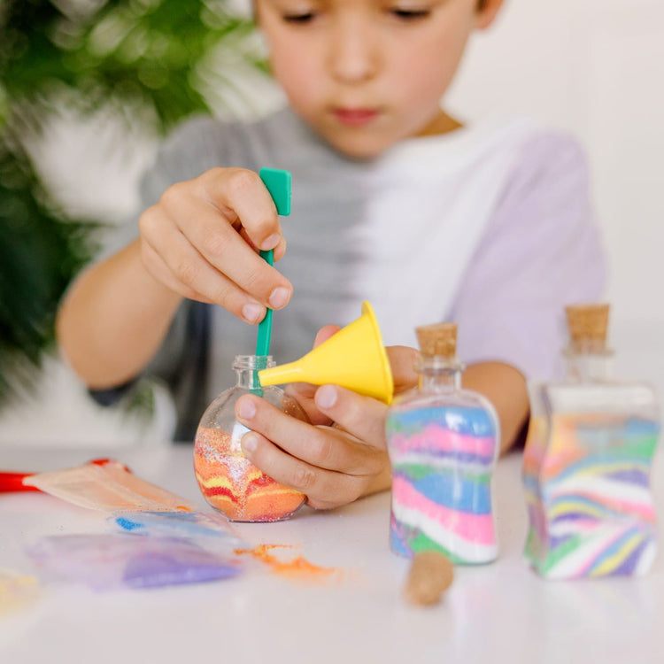 The front of the box for the Melissa & Doug Created by Me! Sand Art Bottles Craft Kit: 3 Bottles, 6 Bags of Colored Sand, Design Tool