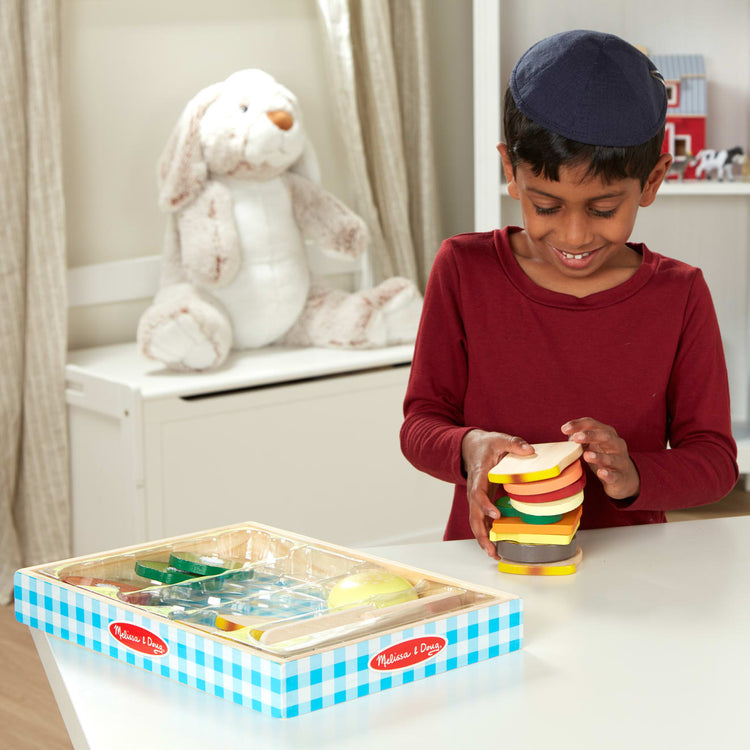 A kid playing with the Melissa & Doug Wooden Sandwich-Making Pretend Play Food Set