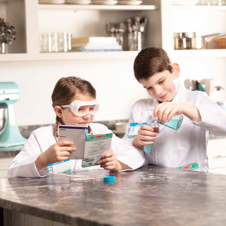 A kid playing with the Melissa & Doug Scientist Role Play Costume Set (X pcs) - Lab Coat, Goggles, 6 Experiments