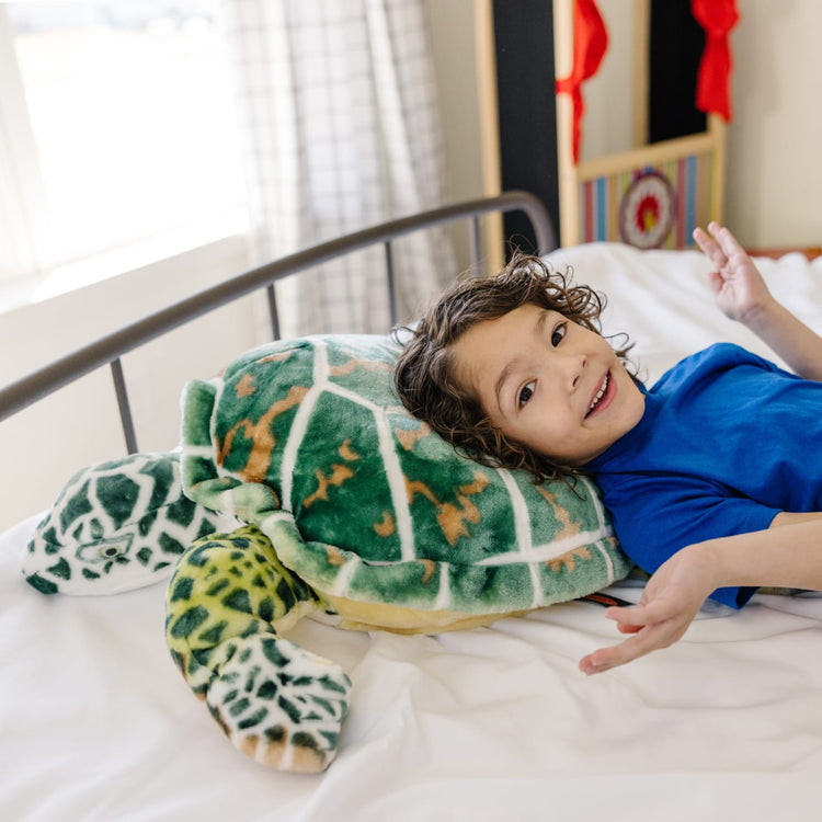 A kid playing with the Melissa & Doug Giant Sea Turtle - Lifelike Stuffed Animal (nearly 3 feet long)