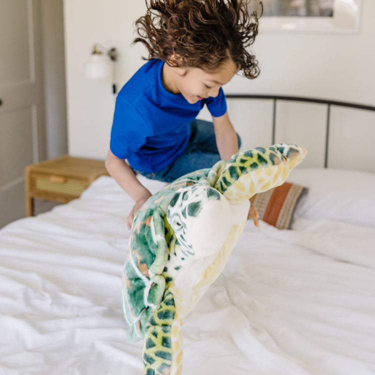 A kid playing with the Melissa & Doug Giant Sea Turtle - Lifelike Stuffed Animal (nearly 3 feet long)