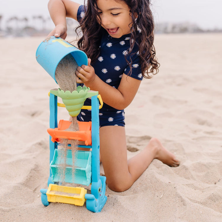 A kid playing with the Melissa & Doug Seaside Sidekicks Sand-and-Water Sifting Funnel