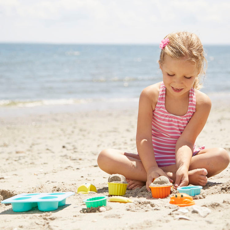 A kid playing with the Melissa & Doug Sunny Patch Seaside Sidekicks Sand Cupcake Play Set