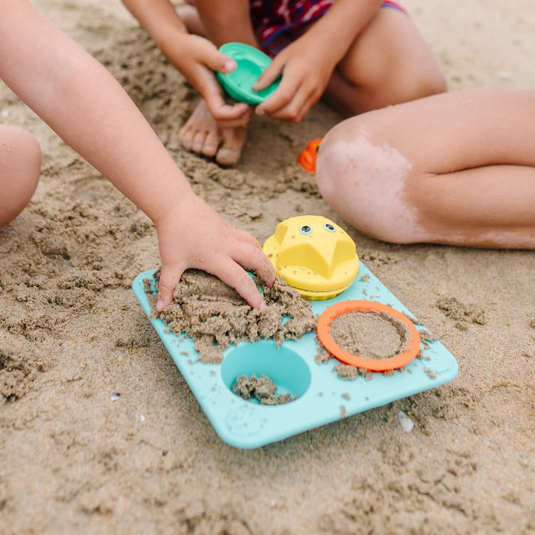 A kid playing with the Melissa & Doug Sunny Patch Seaside Sidekicks Sand Cupcake Play Set