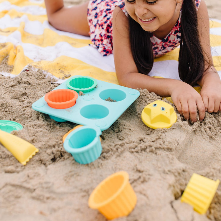 A kid playing with the Melissa & Doug Sunny Patch Seaside Sidekicks Sand Cupcake Play Set