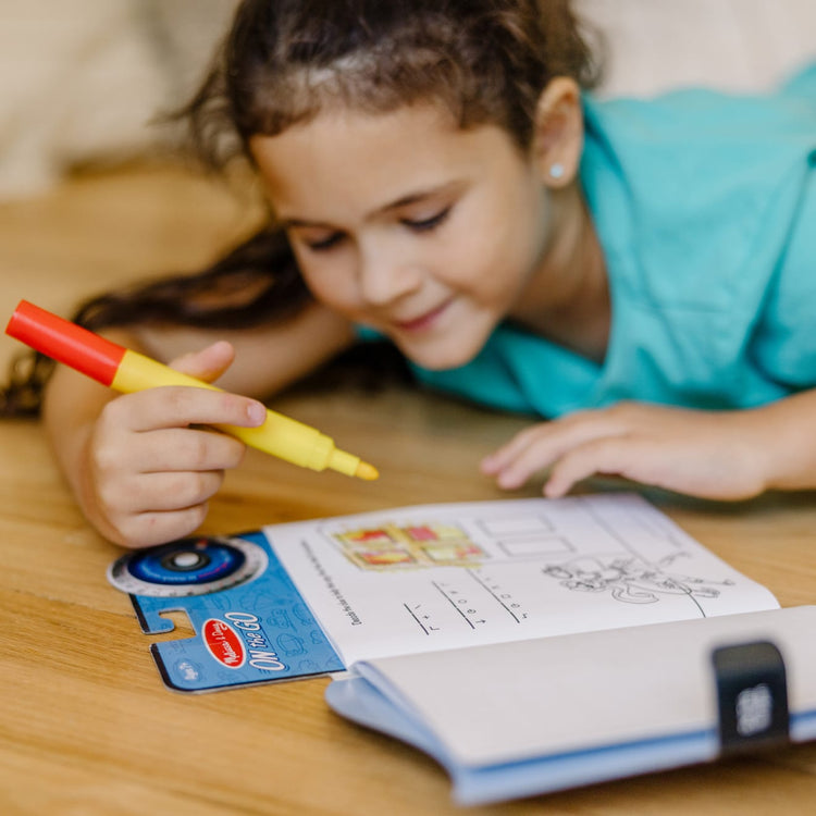 A kid playing with the Melissa & Doug On the Go Spy Mystery Secret Decoder Book With Decoder Wheel and Magic-Reveal Pen