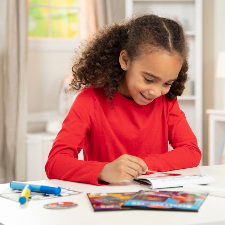 A kid playing with the Melissa & Doug On the Go Secret Decoder Deluxe Activity Set and Super Sleuth Toy