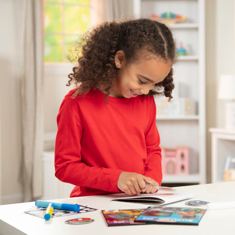 A kid playing with the Melissa & Doug On the Go Secret Decoder Deluxe Activity Set and Super Sleuth Toy