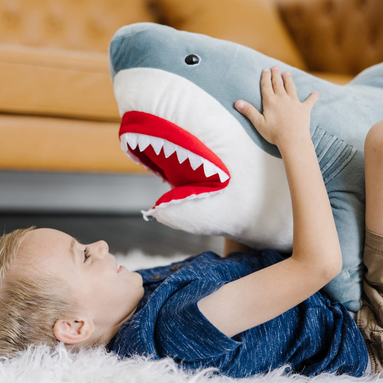 A kid playing with the Melissa & Doug Giant Shark - Lifelike Stuffed Animal (over 3 feet long)