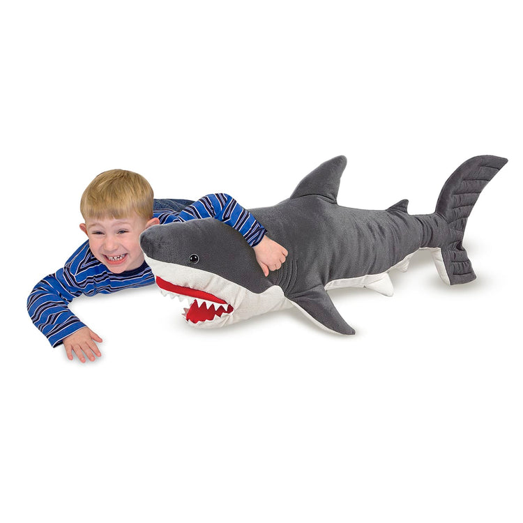 A kid playing with the Melissa & Doug Giant Shark - Lifelike Stuffed Animal (over 3 feet long)