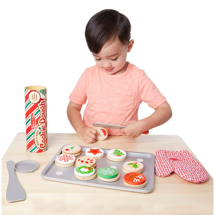 A child on white background with the Melissa & Doug Slice and Bake Wooden Christmas Cookie Play Food Set