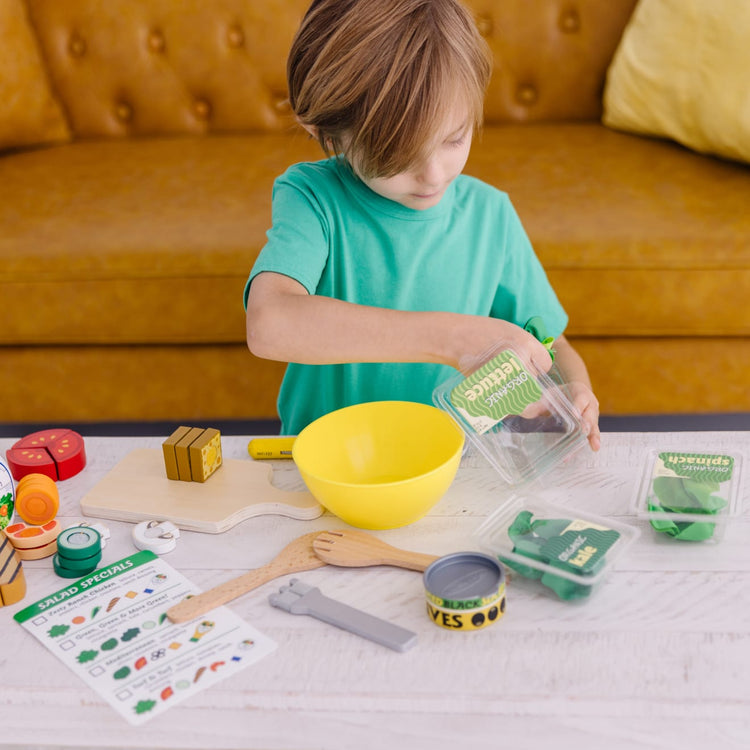 A kid playing with the Melissa & Doug Slice and Toss Salad Play Food Set – 52 Wooden and Felt Pieces