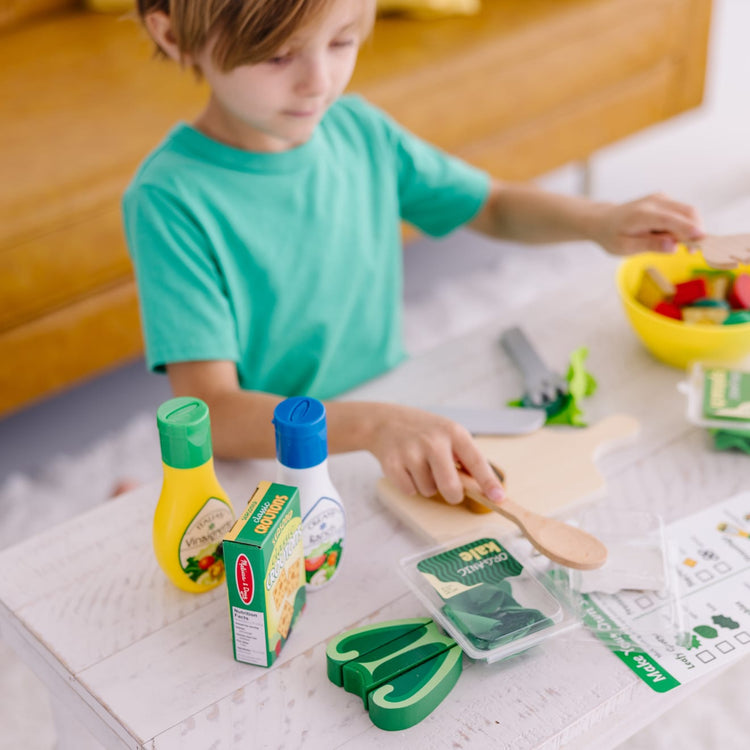 A kid playing with the Melissa & Doug Slice and Toss Salad Play Food Set – 52 Wooden and Felt Pieces