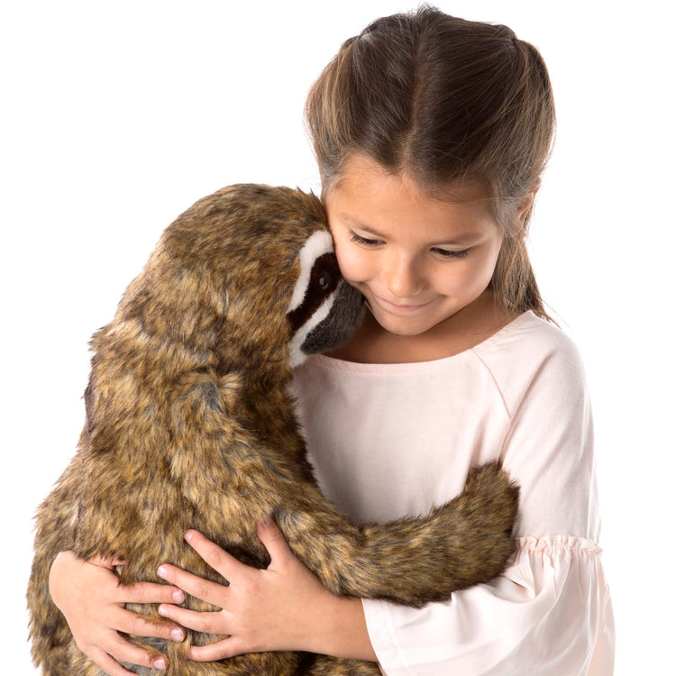 A child on white background with the Melissa & Doug Lifelike Plush Sloth Stuffed Animal (12W x 14.5H x 9D in)