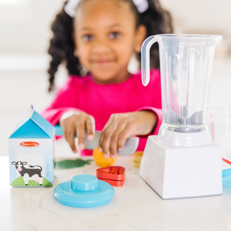 A kid playing with the Melissa & Doug Smoothie Maker Blender Set with Play Food (222 Pcs)