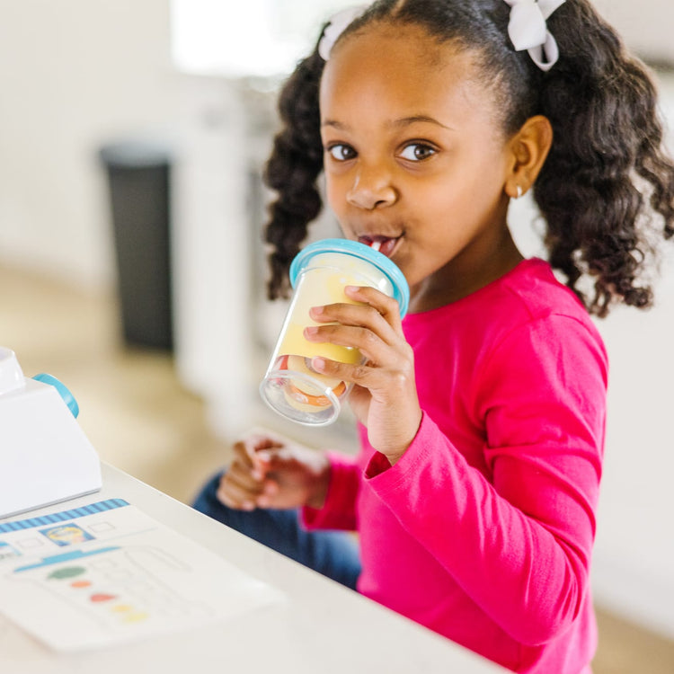 A kid playing with the Melissa & Doug Smoothie Maker Blender Set with Play Food (222 Pcs)