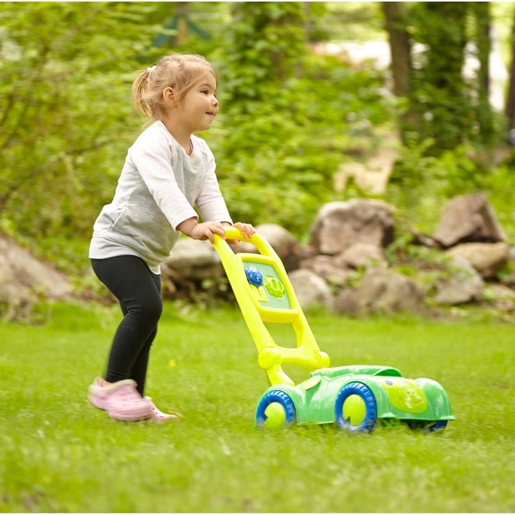 A kid playing with the Melissa & Doug Sunny Patch Snappy Turtle Lawn Mower - Pretend Play Toy for Kids