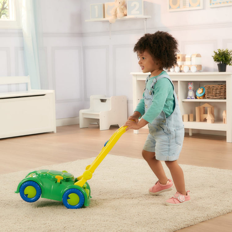 A kid playing with the Melissa & Doug Sunny Patch Snappy Turtle Lawn Mower - Pretend Play Toy for Kids