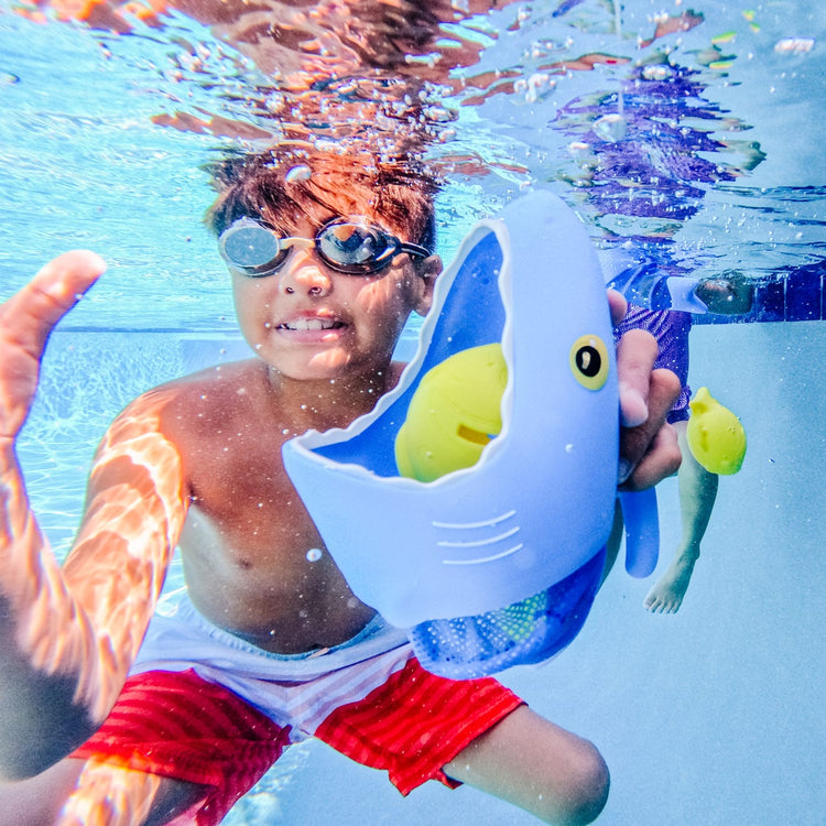 A kid playing with the Melissa & Doug Sunny Patch Spark Shark Fish Hunt Pool Game With 2 Nets and 6 Fish to Catch