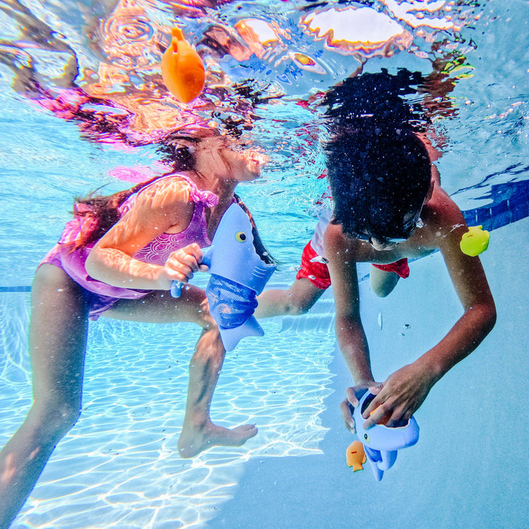 A kid playing with the Melissa & Doug Sunny Patch Spark Shark Fish Hunt Pool Game With 2 Nets and 6 Fish to Catch