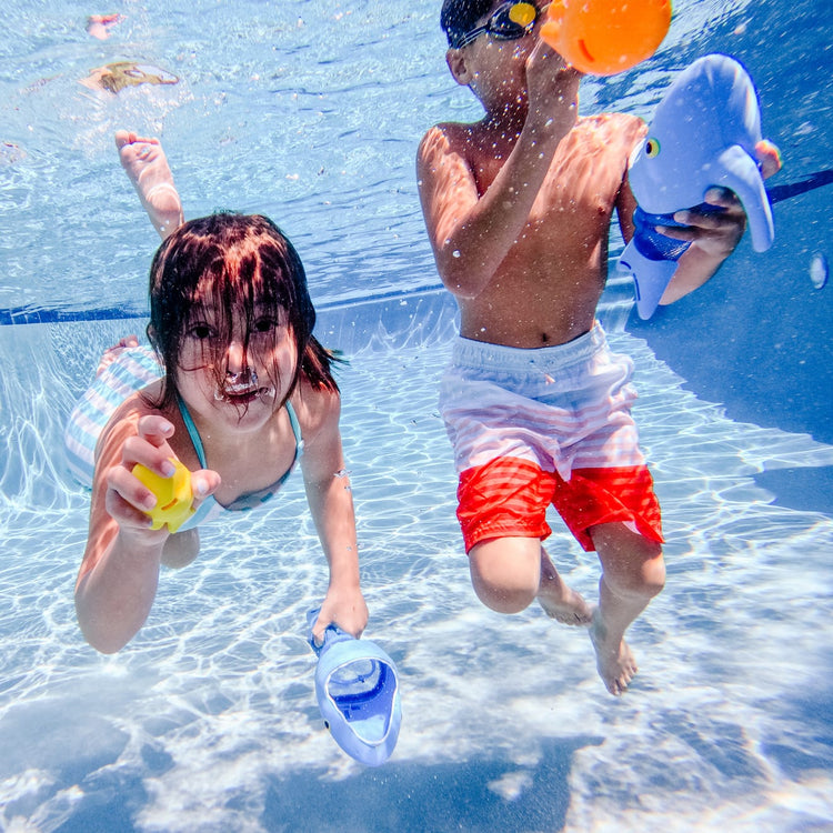 A kid playing with the Melissa & Doug Sunny Patch Spark Shark Fish Hunt Pool Game With 2 Nets and 6 Fish to Catch