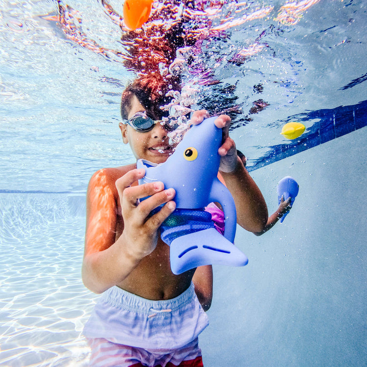 A kid playing with the Melissa & Doug Sunny Patch Spark Shark Fish Hunt Pool Game With 2 Nets and 6 Fish to Catch