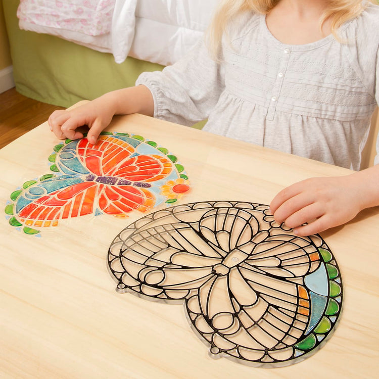 A kid playing with the Melissa & Doug Stained Glass Made Easy Activity Kit: Butterfly - 140+ Stickers