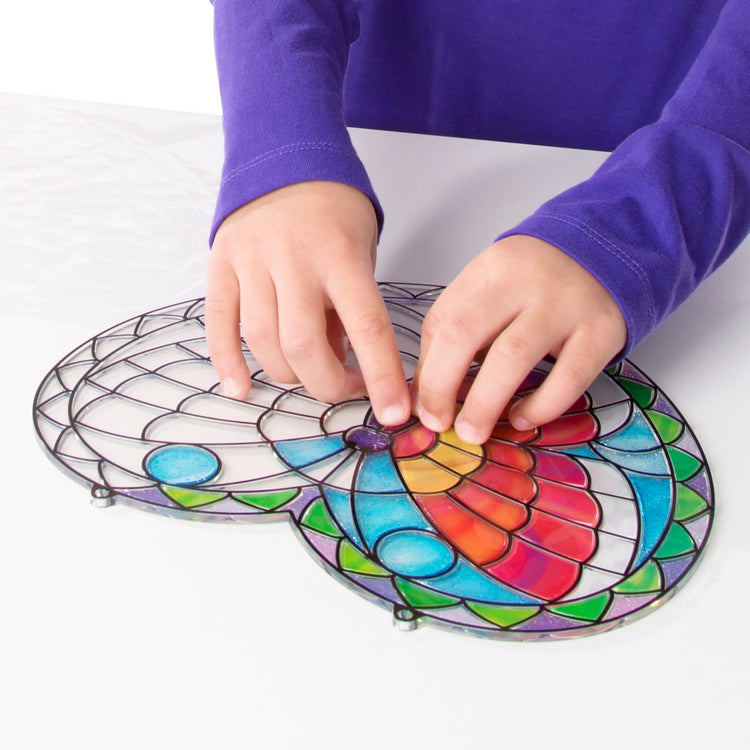 A child on white background with the Melissa & Doug Stained Glass Made Easy Activity Kit: Butterfly - 140+ Stickers