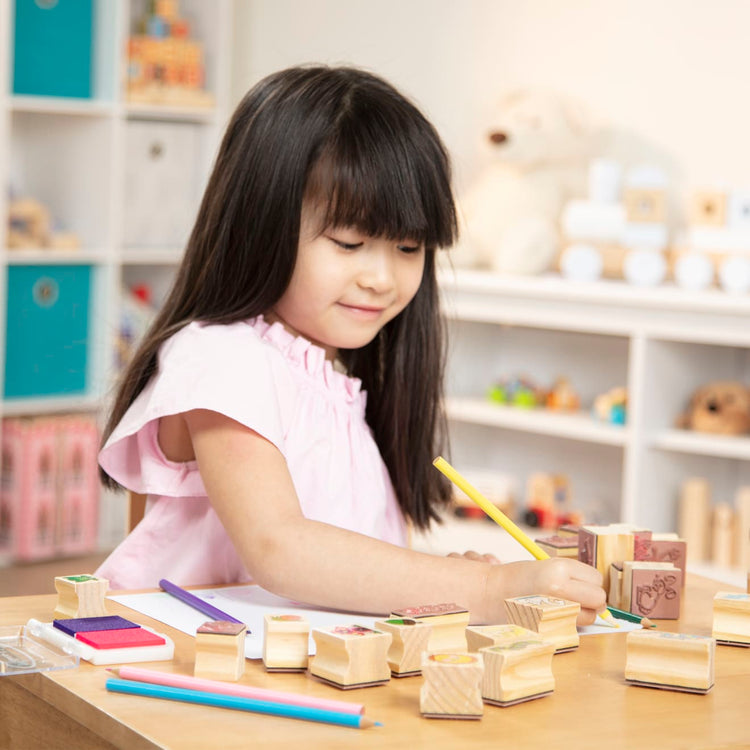 The front of the box for the Melissa & Doug Stamp-a-Scene Stamp Pad: Fairy Garden - 20 Wooden Stamps, 5 Colored Pencils, and 2-Color Stamp Pad