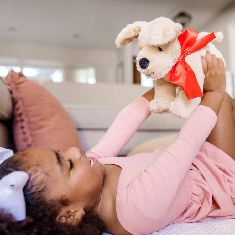 A kid playing with the Melissa & Doug Sunny Yellow Lab - Stuffed Animal Puppy Dog