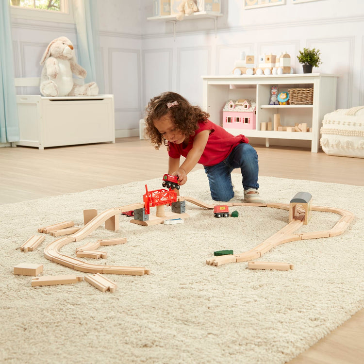 A kid playing with the Melissa & Doug Swivel Bridge Wooden Train Set (47 pcs)