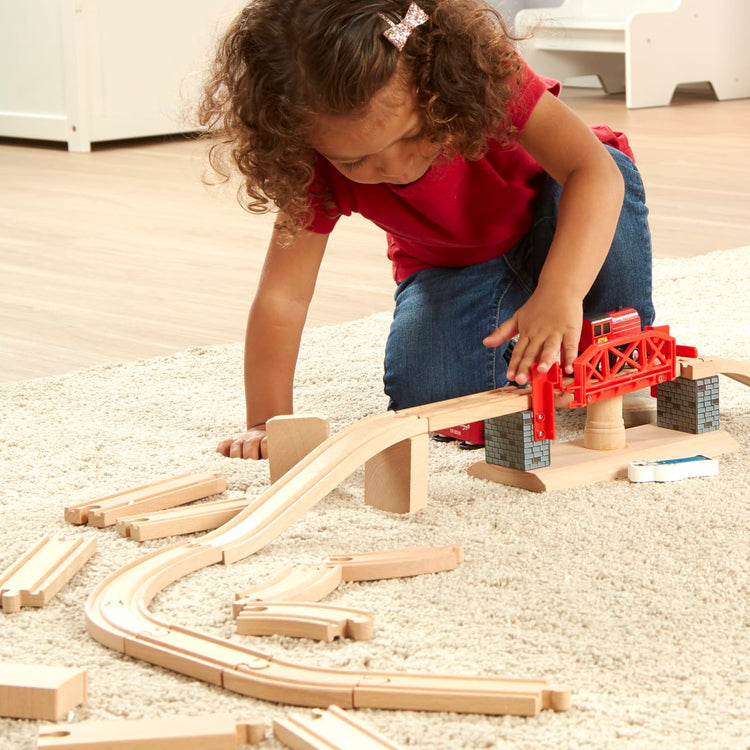 A kid playing with the Melissa & Doug Swivel Bridge Wooden Train Set (47 pcs)