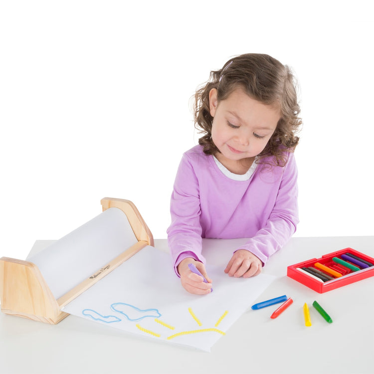 A child on white background with the Melissa & Doug Wooden Tabletop Paper Roll Dispenser With White Bond Paper (12 inches x 75 feet)