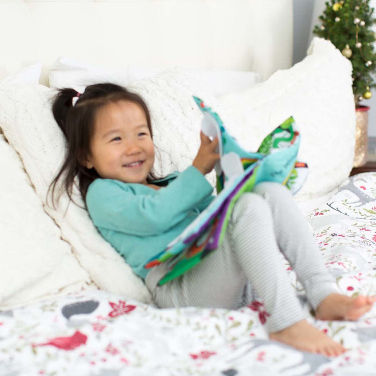 A kid playing with the Melissa & Doug Soft Activity Baby Book - The Wonderful World of Peekaboo!