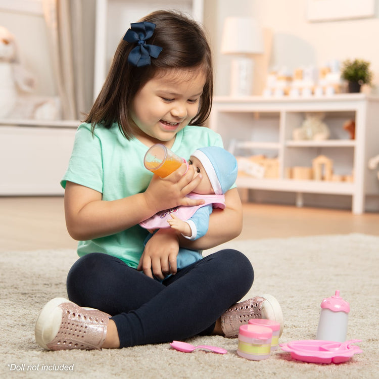 A kid playing with the Melissa & Doug Mine to Love Baby Food & Bottle Play Set