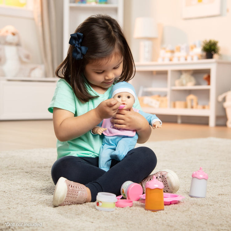 A kid playing with the Melissa & Doug Mine to Love Baby Food & Bottle Play Set