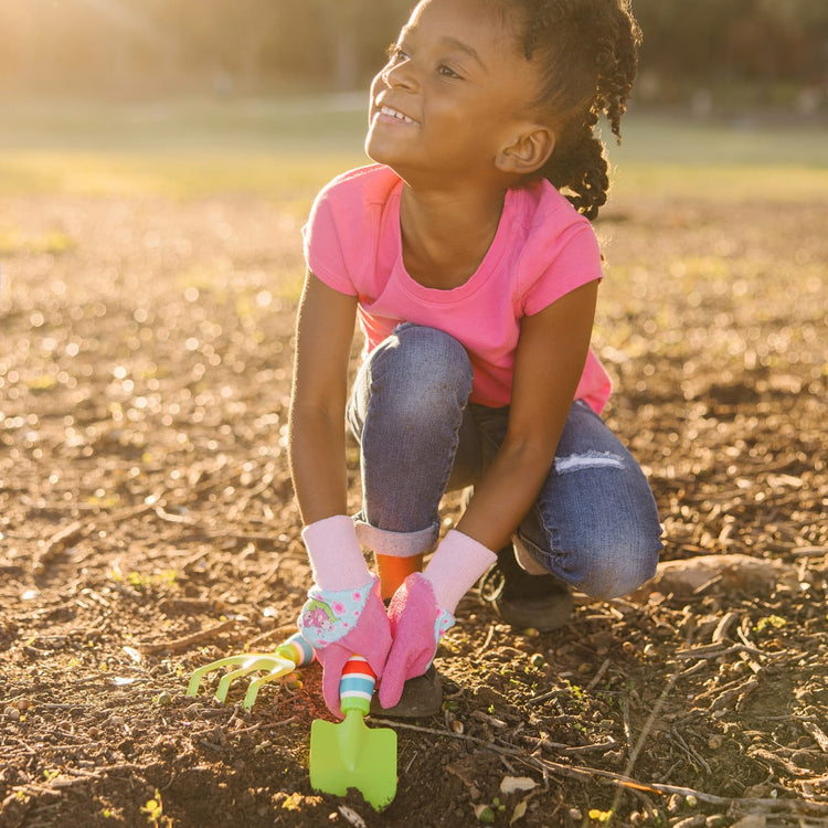 A kid playing with the Melissa & Doug Dixie and Trixie Ladybug Good Gripping Gardening Gloves